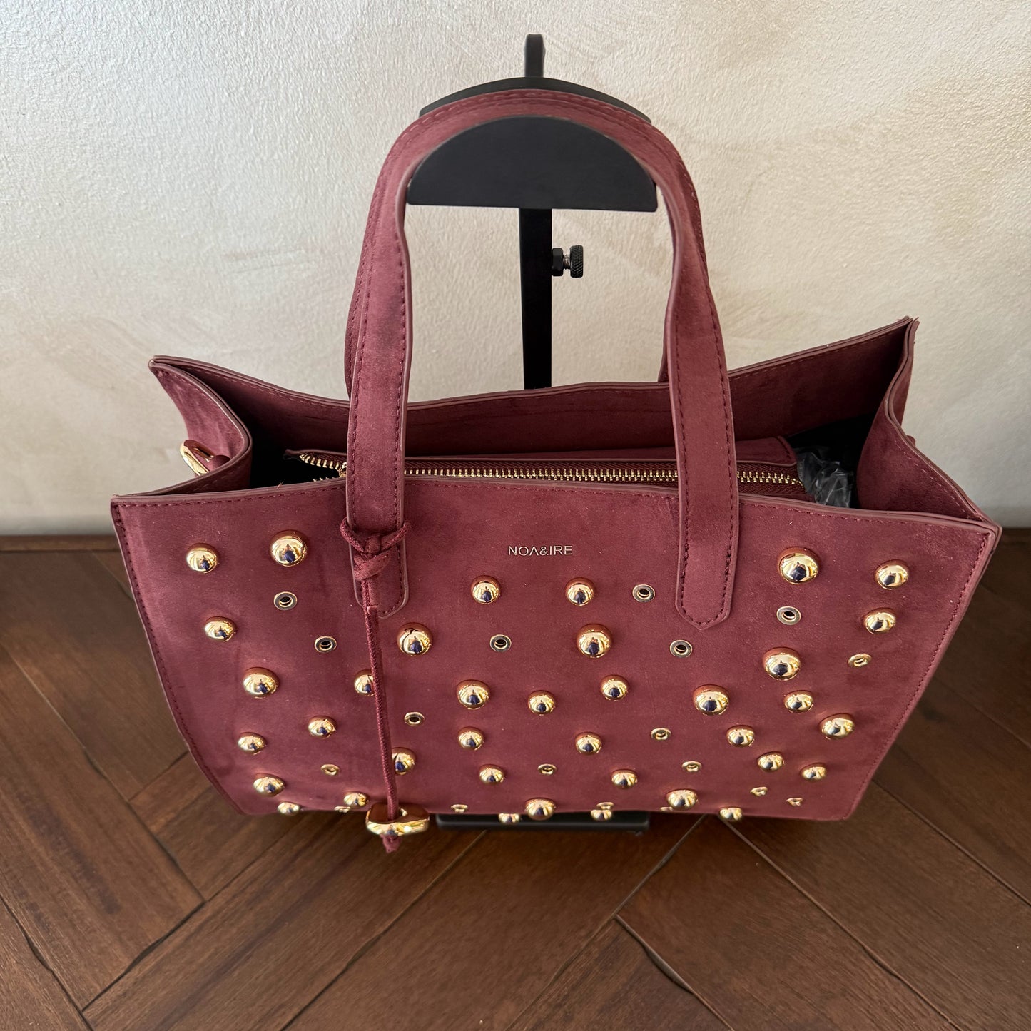 Bolso shopper con tachuelas metálicas con asa de mano y larga para colgar.