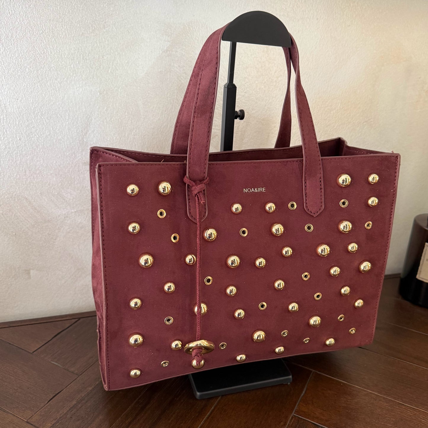 Bolso shopper con tachuelas metálicas con asa de mano y larga para colgar.