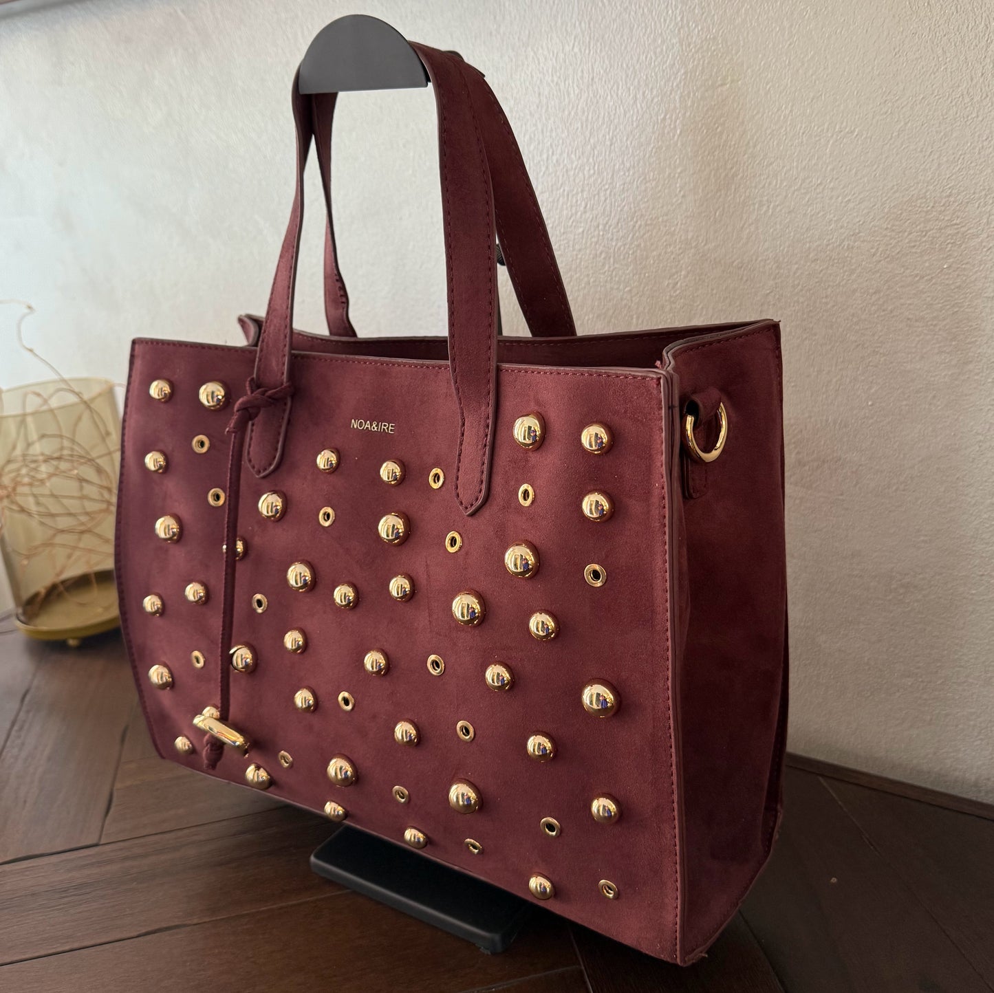Bolso shopper con tachuelas metálicas con asa de mano y larga para colgar.