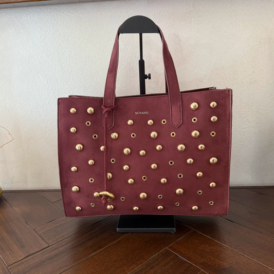 Bolso shopper con tachuelas metálicas con asa de mano y larga para colgar.