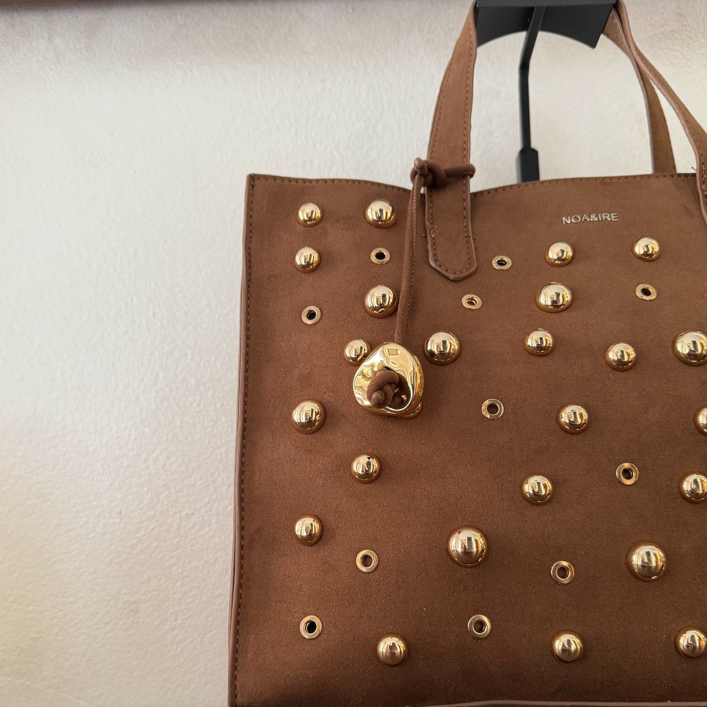 Bolso shopper con tachuelas metálicas con asa de mano y larga para colgar.