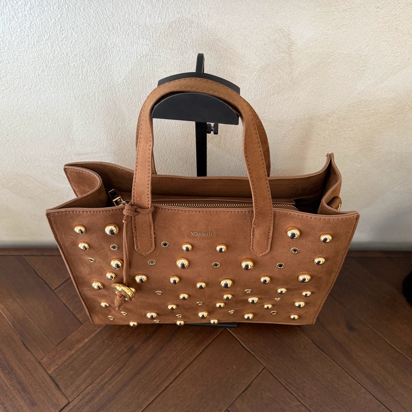 Bolso shopper con tachuelas metálicas con asa de mano y larga para colgar.