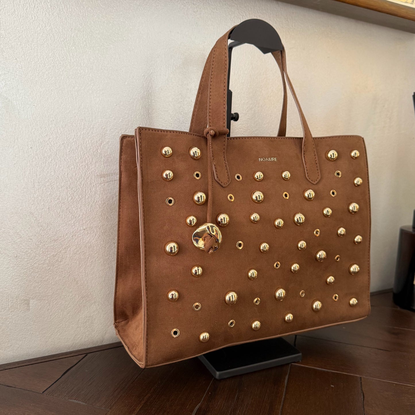 Bolso shopper con tachuelas metálicas con asa de mano y larga para colgar.