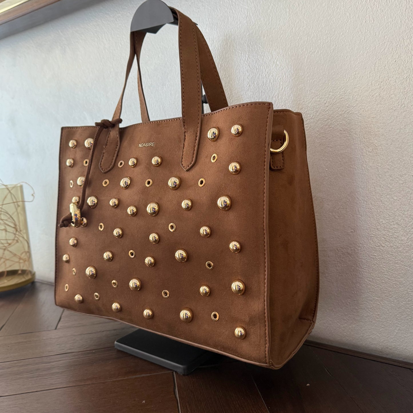 Bolso shopper con tachuelas metálicas con asa de mano y larga para colgar.