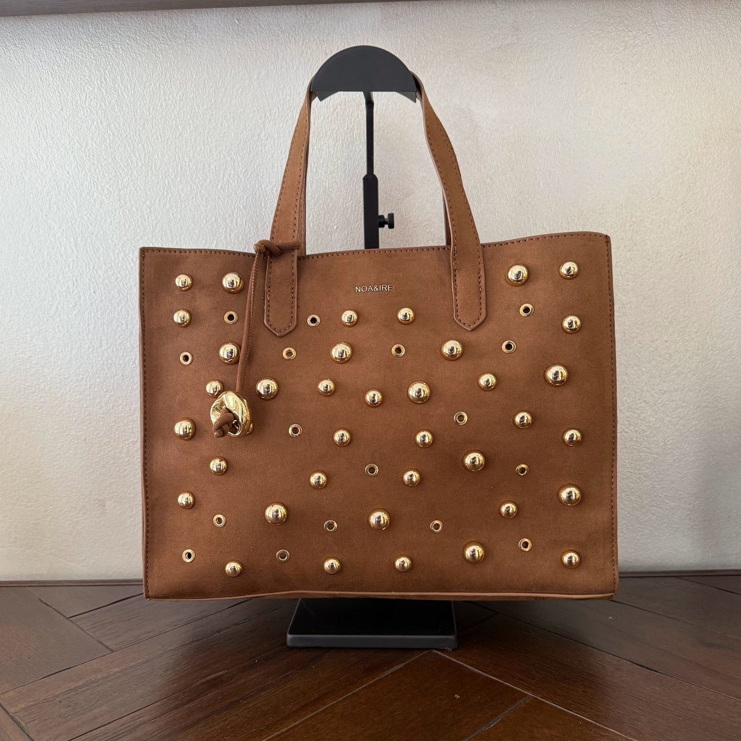 Bolso shopper con tachuelas metálicas con asa de mano y larga para colgar.