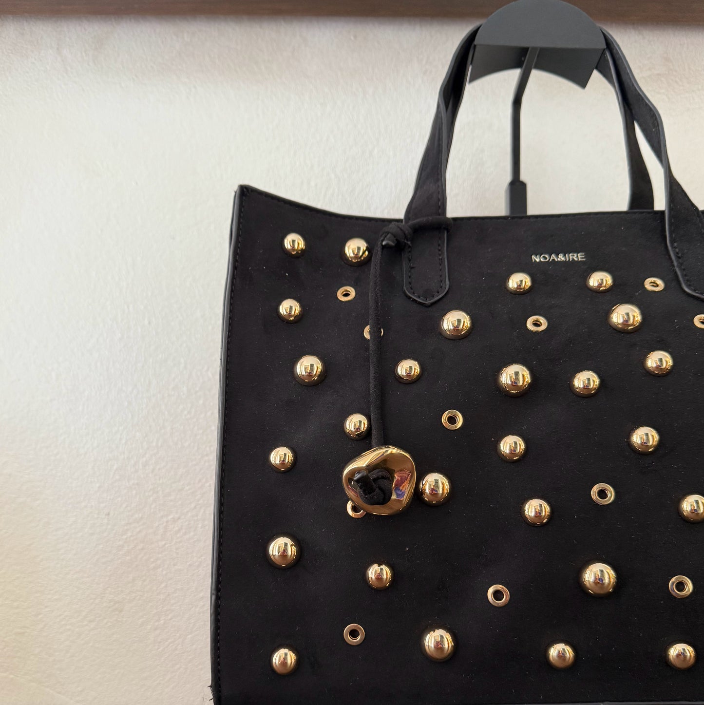 Bolso shopper con tachuelas metálicas con asa de mano y larga para colgar.