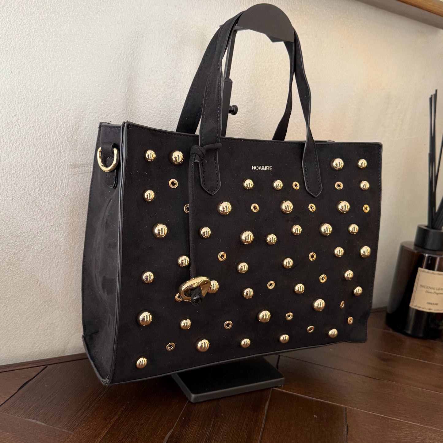 Bolso shopper con tachuelas metálicas con asa de mano y larga para colgar.