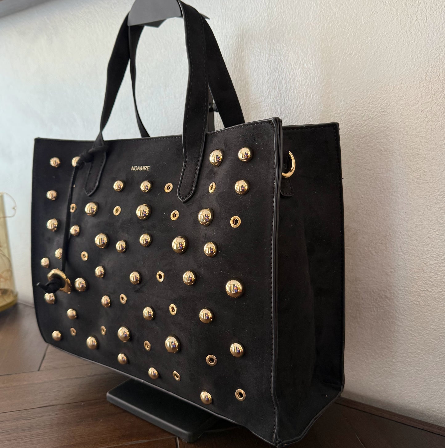 Bolso shopper con tachuelas metálicas con asa de mano y larga para colgar.