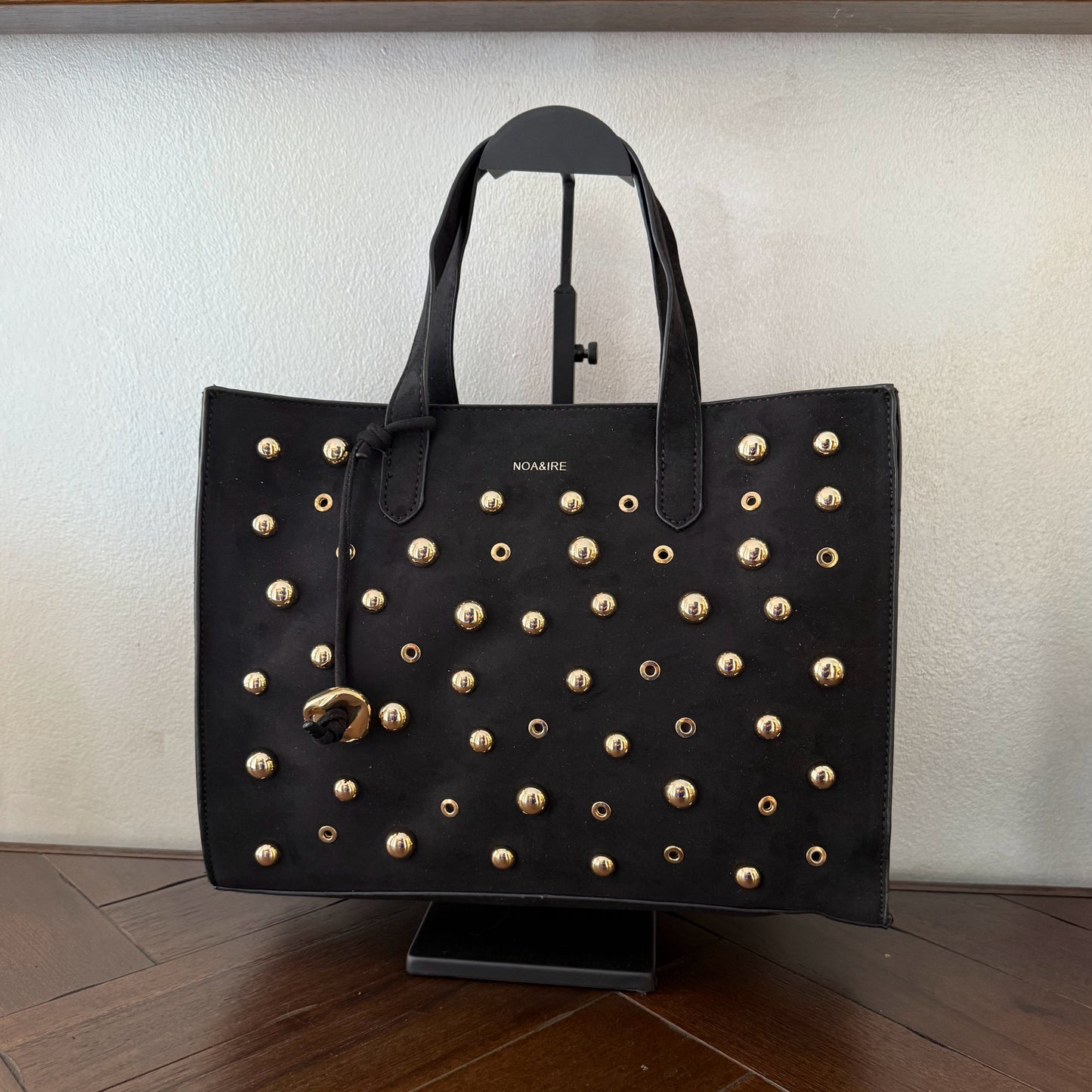 Bolso shopper con tachuelas metálicas con asa de mano y larga para colgar.