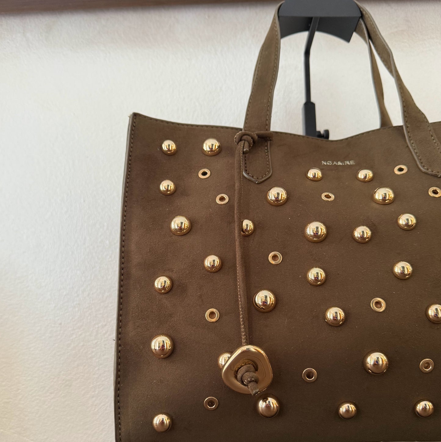Bolso shopper con tachuelas metálicas con asa de mano y larga para colgar.
