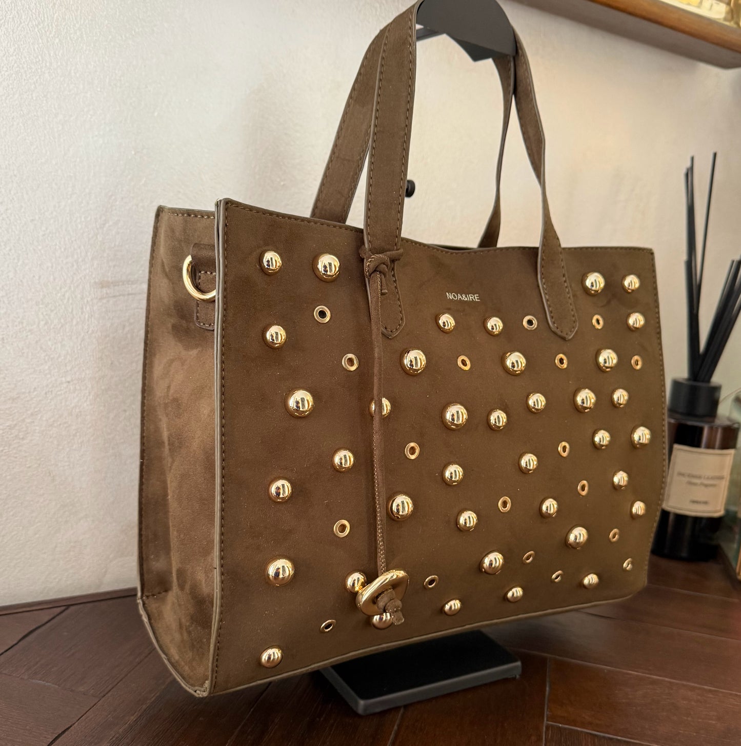 Bolso shopper con tachuelas metálicas con asa de mano y larga para colgar.