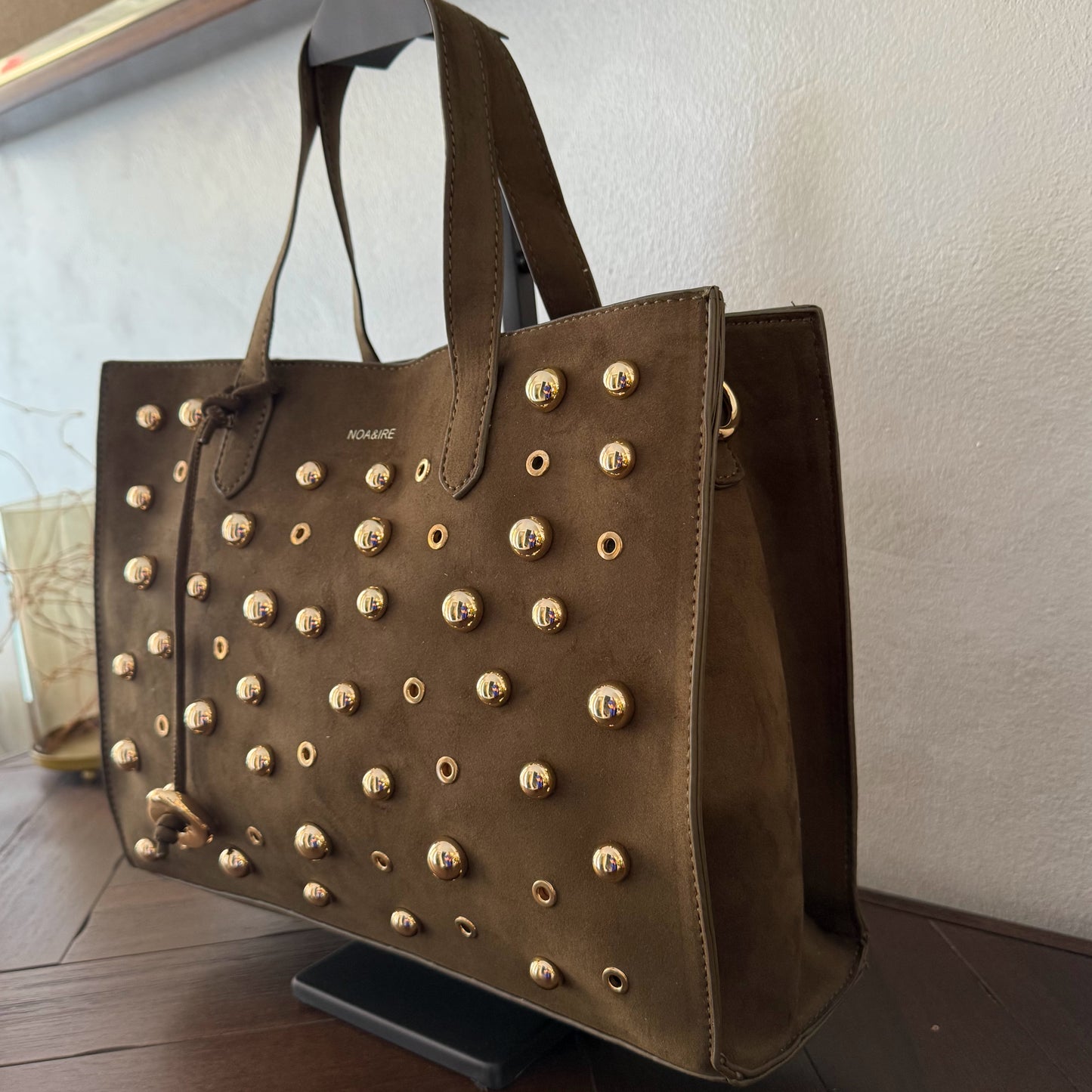 Bolso shopper con tachuelas metálicas con asa de mano y larga para colgar.