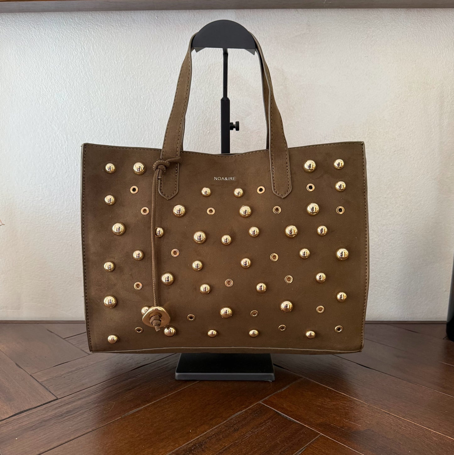 Bolso shopper con tachuelas metálicas con asa de mano y larga para colgar.