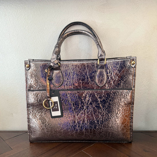 Cartera metalizada con con asa de mano y asa larga.
