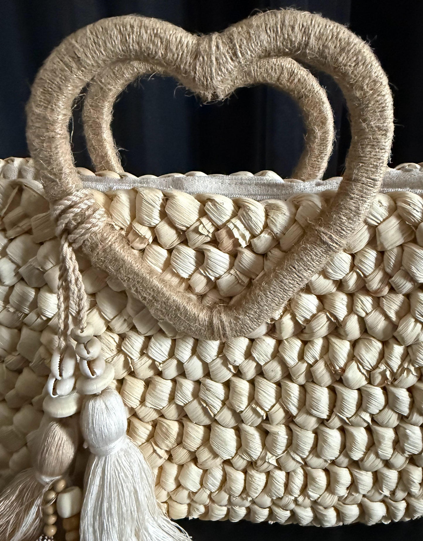 Capazo trenzado con asa en forma de corazón y detalles boho, perfecto para un estilo romántico y veraniego