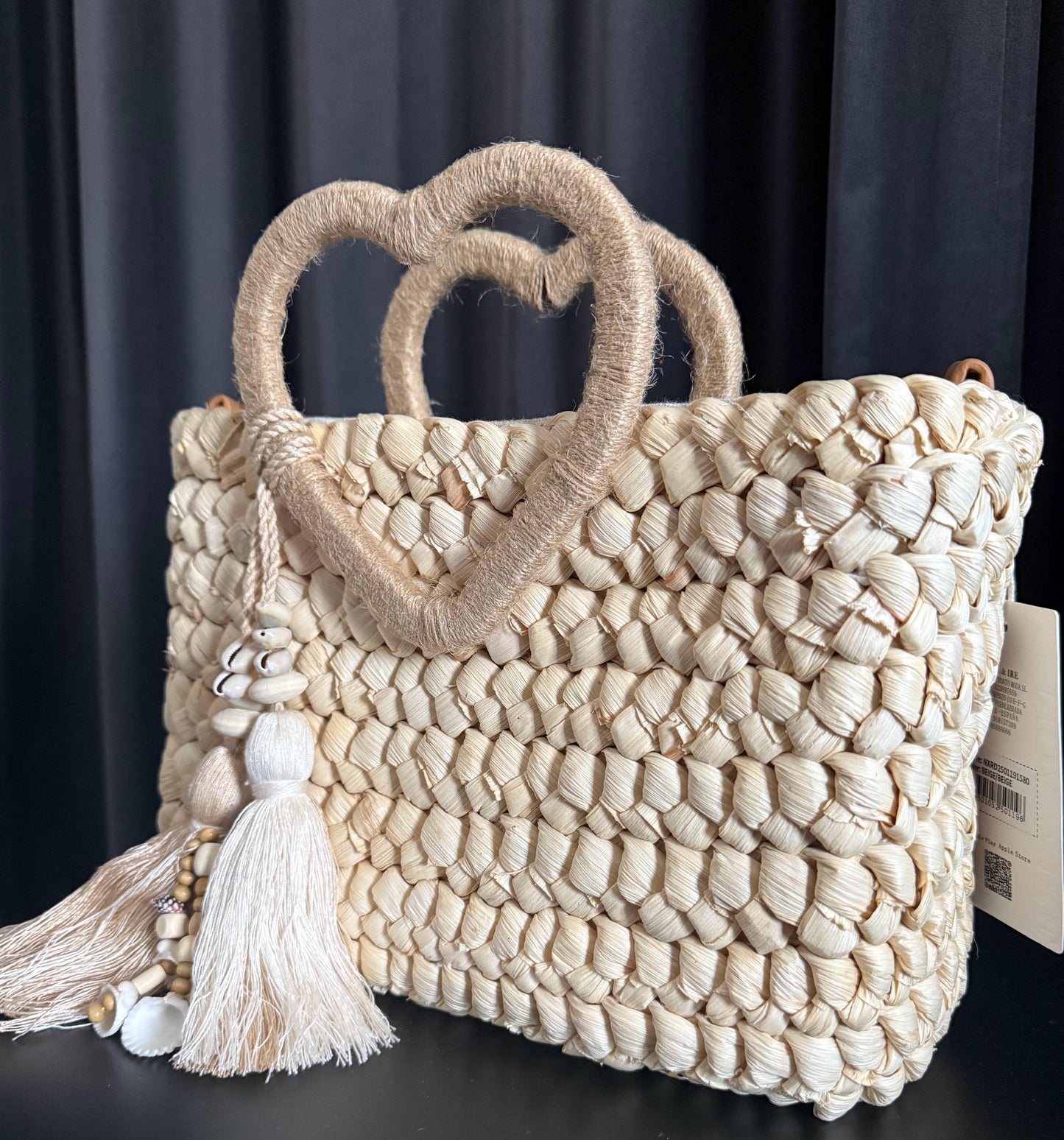 Capazo trenzado con asa en forma de corazón y detalles boho, perfecto para un estilo romántico y veraniego