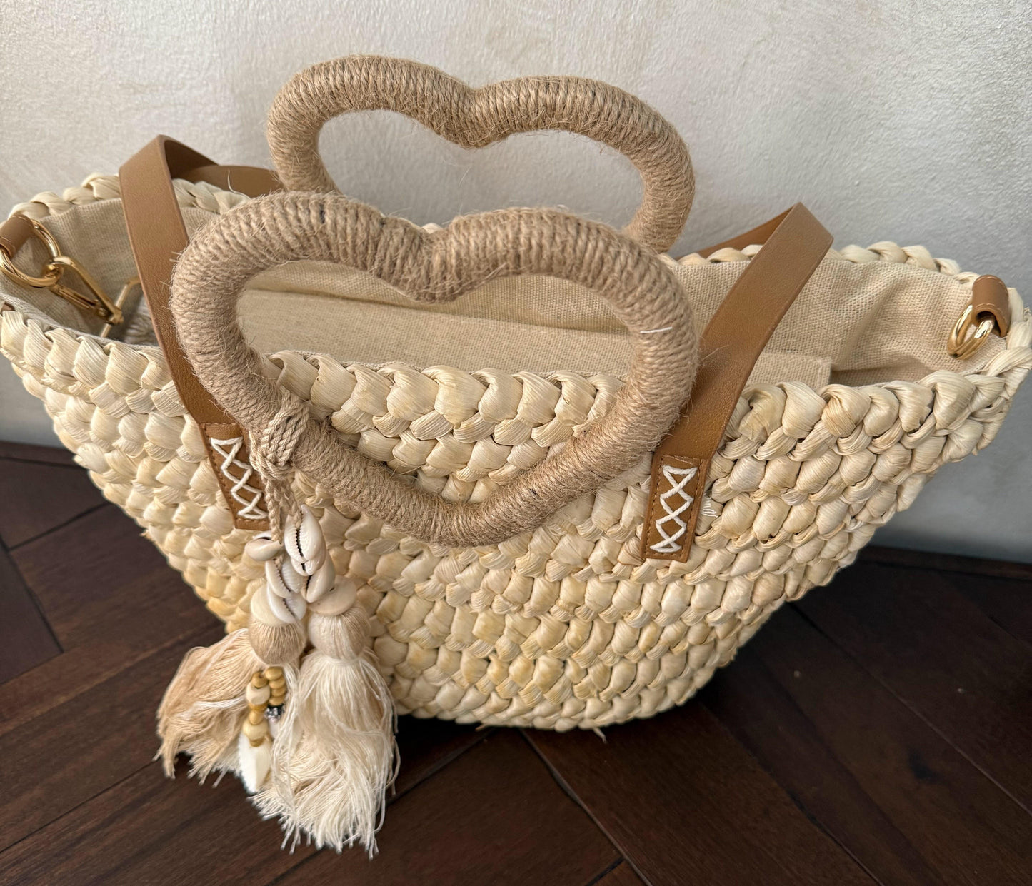 Capazo trenzado con asa en forma de corazón y detalles boho, perfecto para un estilo romántico y veraniego.
