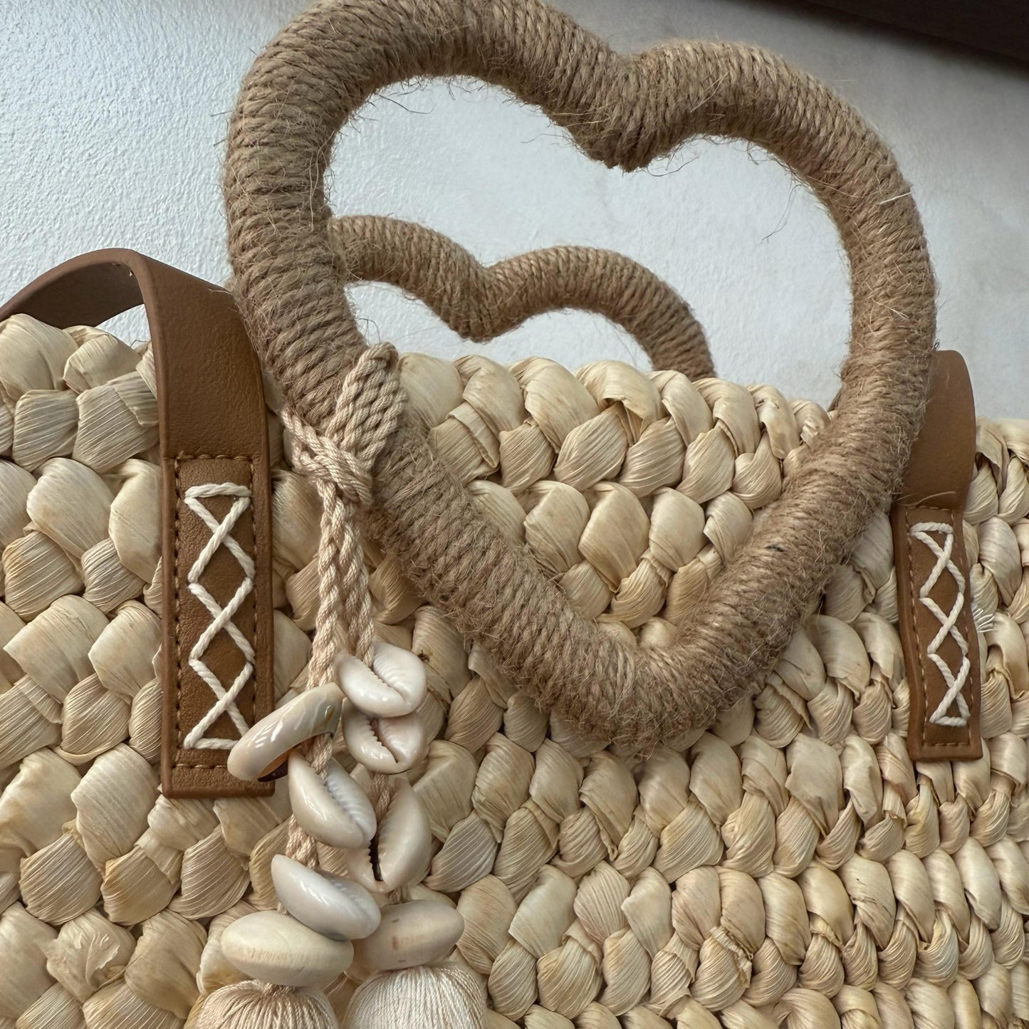 Capazo trenzado con asa en forma de corazón y detalles boho, perfecto para un estilo romántico y veraniego.