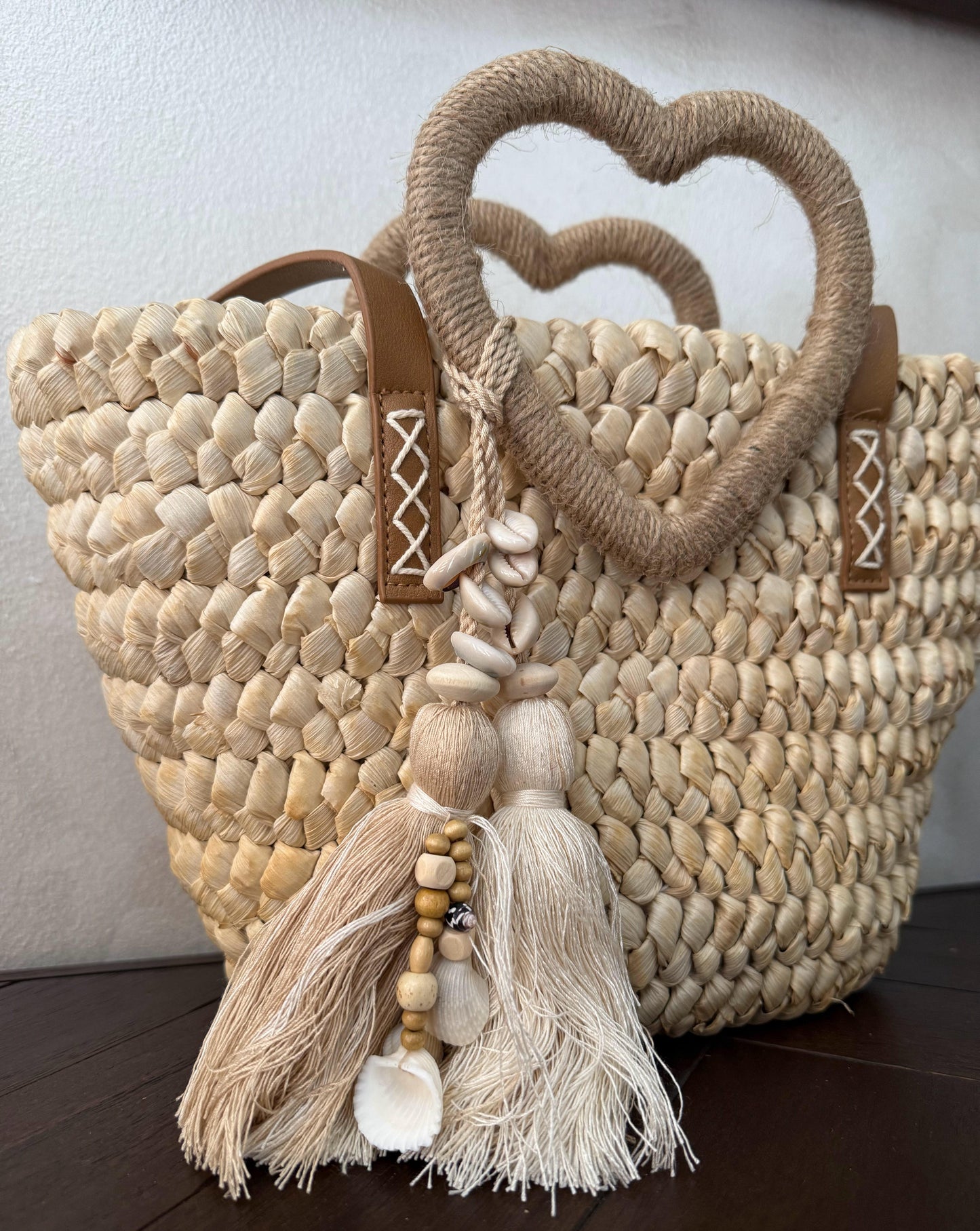 Capazo trenzado con asa en forma de corazón y detalles boho, perfecto para un estilo romántico y veraniego.
