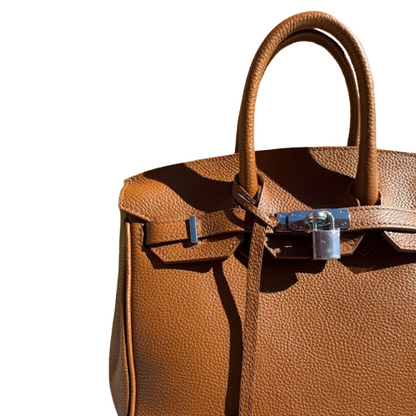 Bolso de piel de mano y cierre metálico.