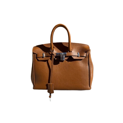 Bolso de piel de mano y cierre metálico.