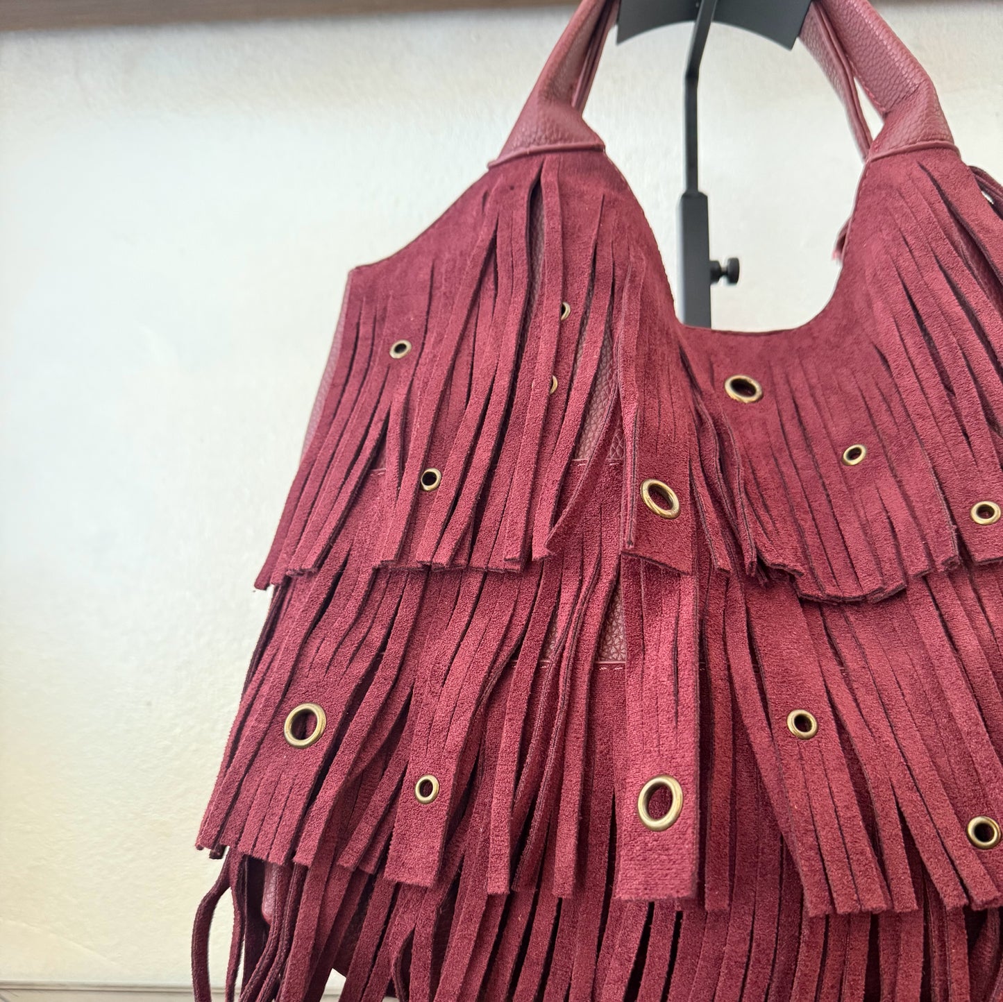 Bolso de mano con asa larga de flecos y aros metálicos