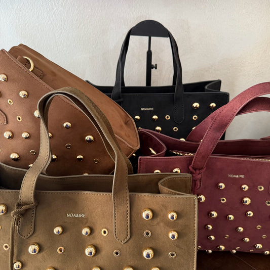 Bolso shopper con tachuelas metálicas con asa de mano y larga para colgar.