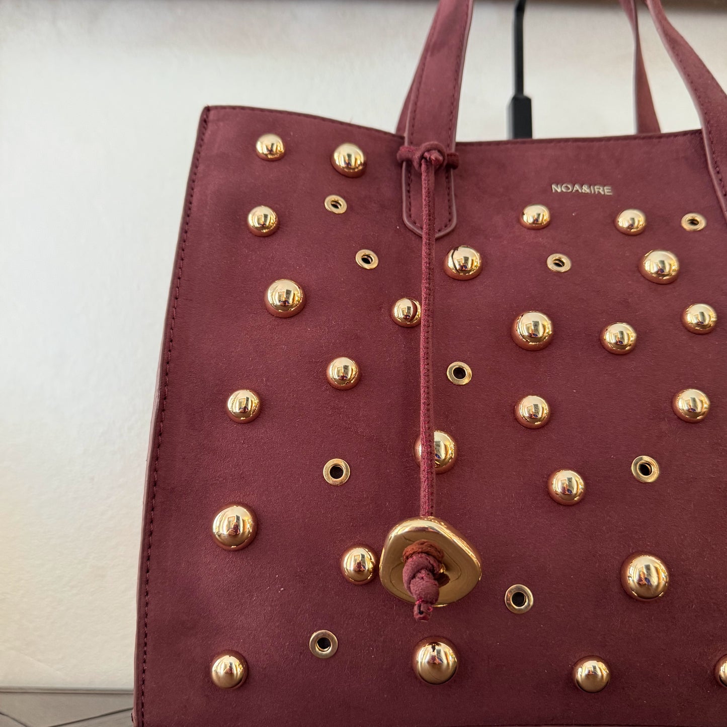 Bolso shopper con tachuelas metálicas con asa de mano y larga para colgar.