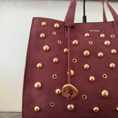 Bolso shopper con tachuelas metálicas con asa de mano y larga para colgar.