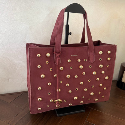 Bolso shopper con tachuelas metálicas con asa de mano y larga para colgar.