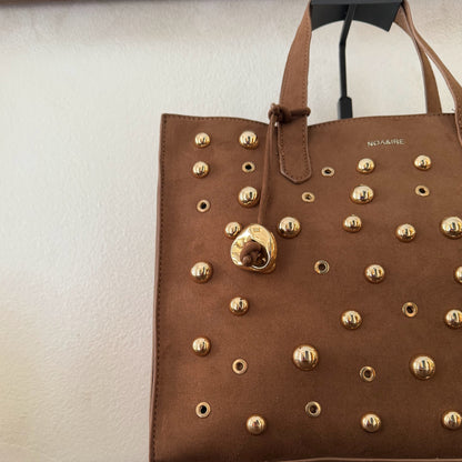 Bolso shopper con tachuelas metálicas con asa de mano y larga para colgar.