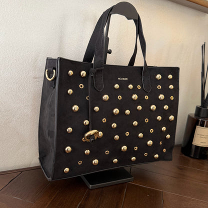 Bolso shopper con tachuelas metálicas con asa de mano y larga para colgar.