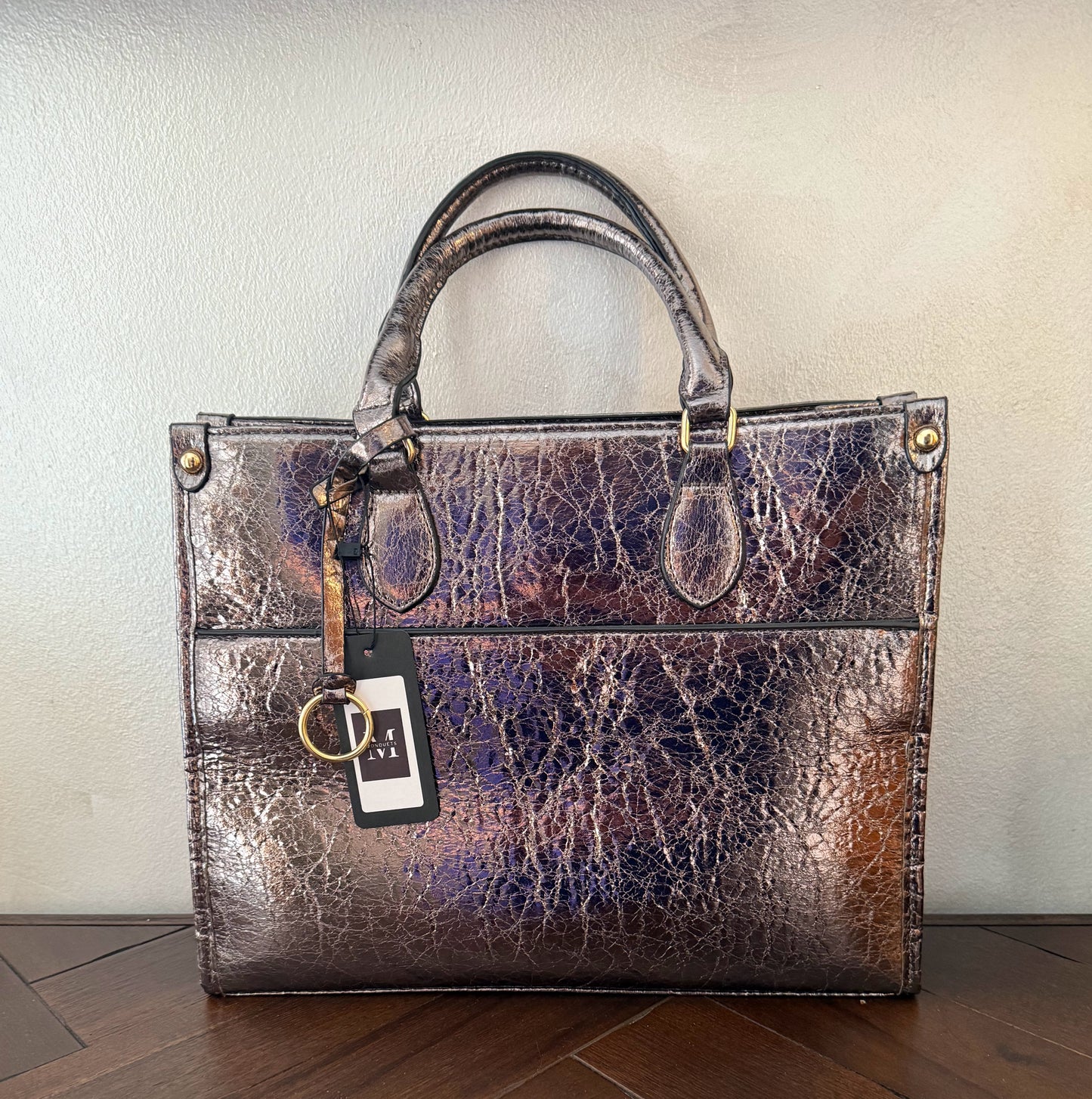 Cartera metalizada con con asa de mano y asa larga.