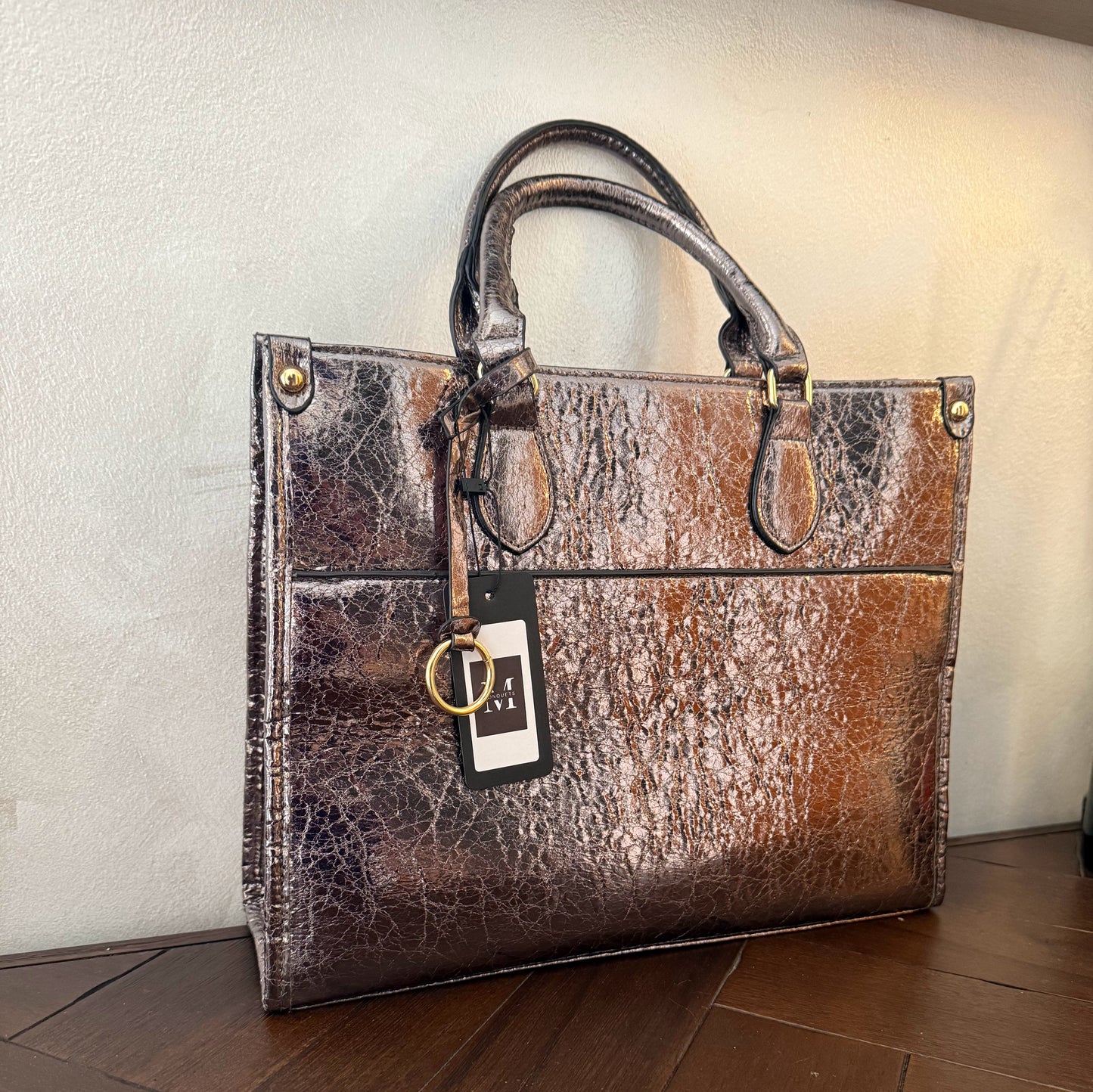 Cartera metalizada con con asa de mano y asa larga.