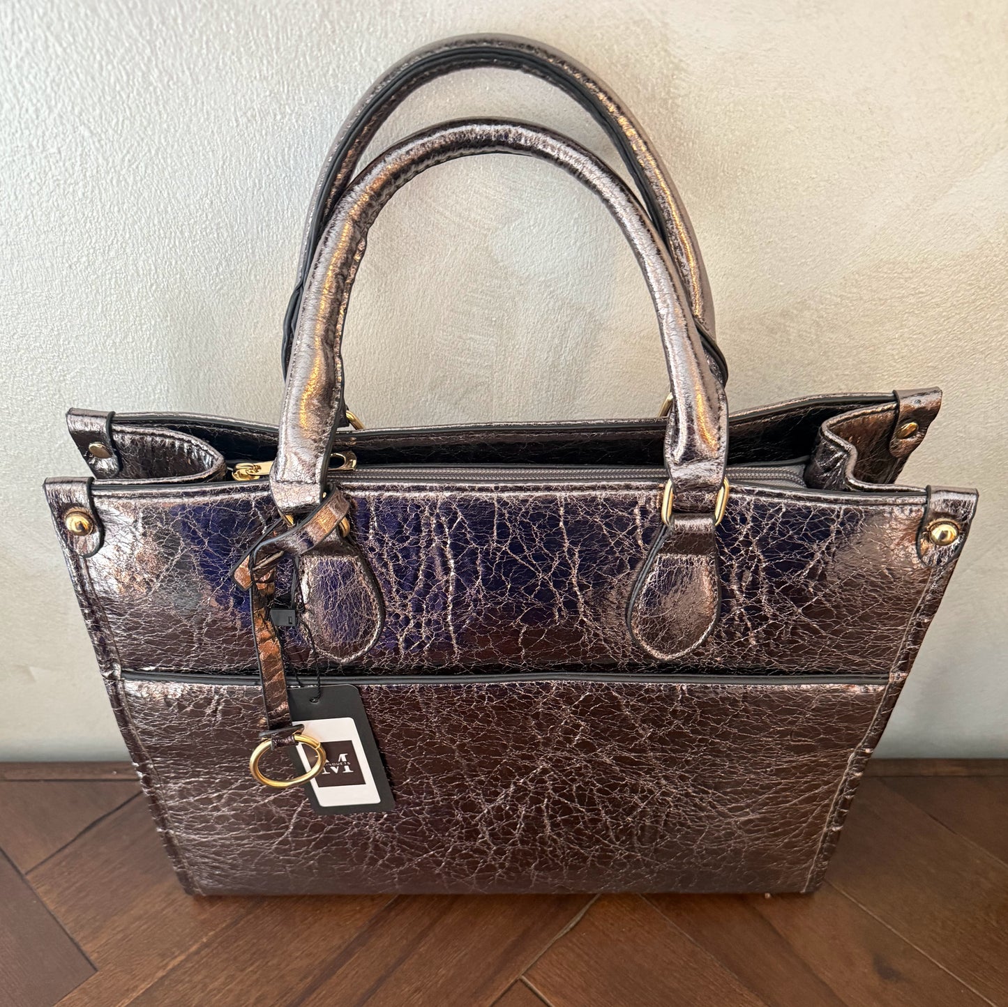 Cartera metalizada con con asa de mano y asa larga.