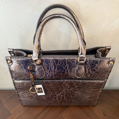 Cartera metalizada con con asa de mano y asa larga.