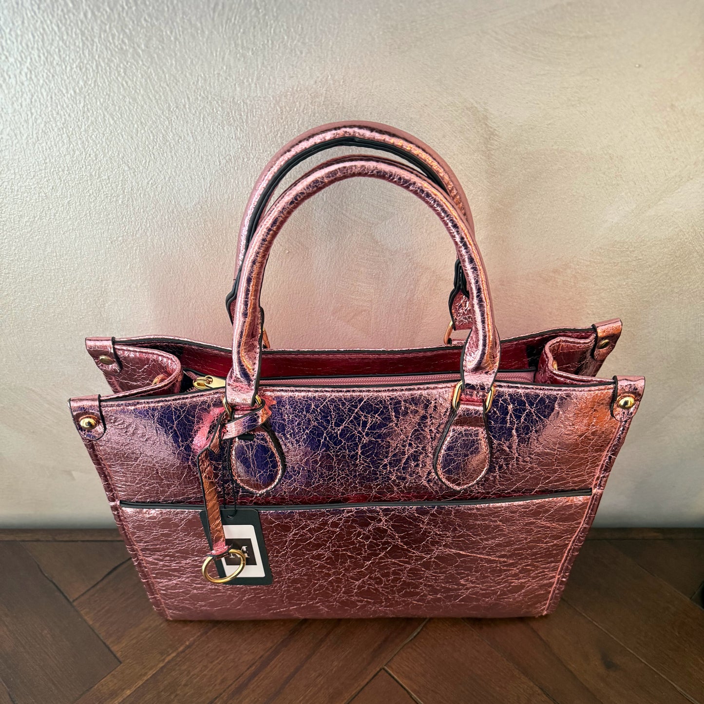 Cartera metalizada con con asa de mano y asa larga.