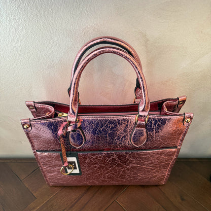 Cartera metalizada con con asa de mano y asa larga.