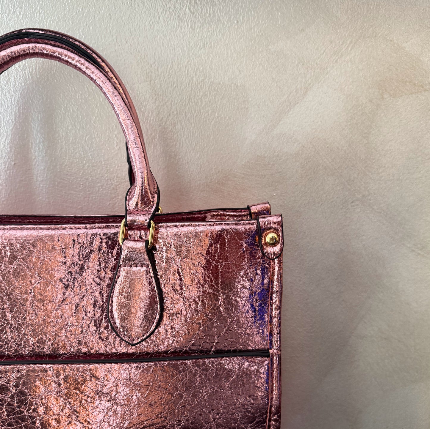 Cartera metalizada con con asa de mano y asa larga.