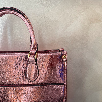Cartera metalizada con con asa de mano y asa larga.