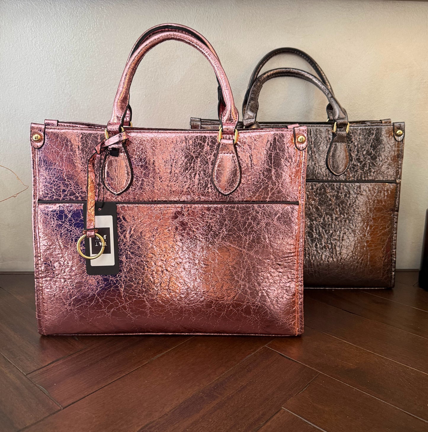 Cartera metalizada con con asa de mano y asa larga.