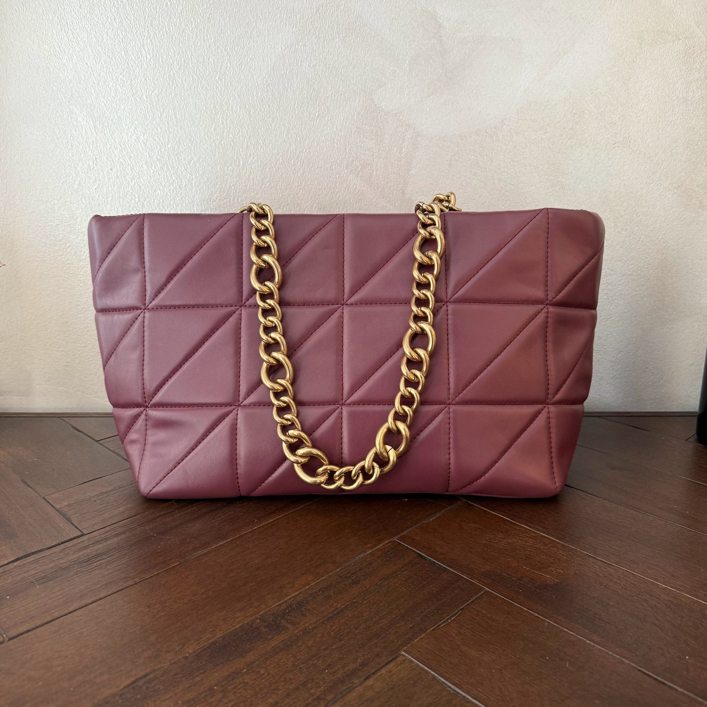 Bolso acolchado con asas de cadena dorada.