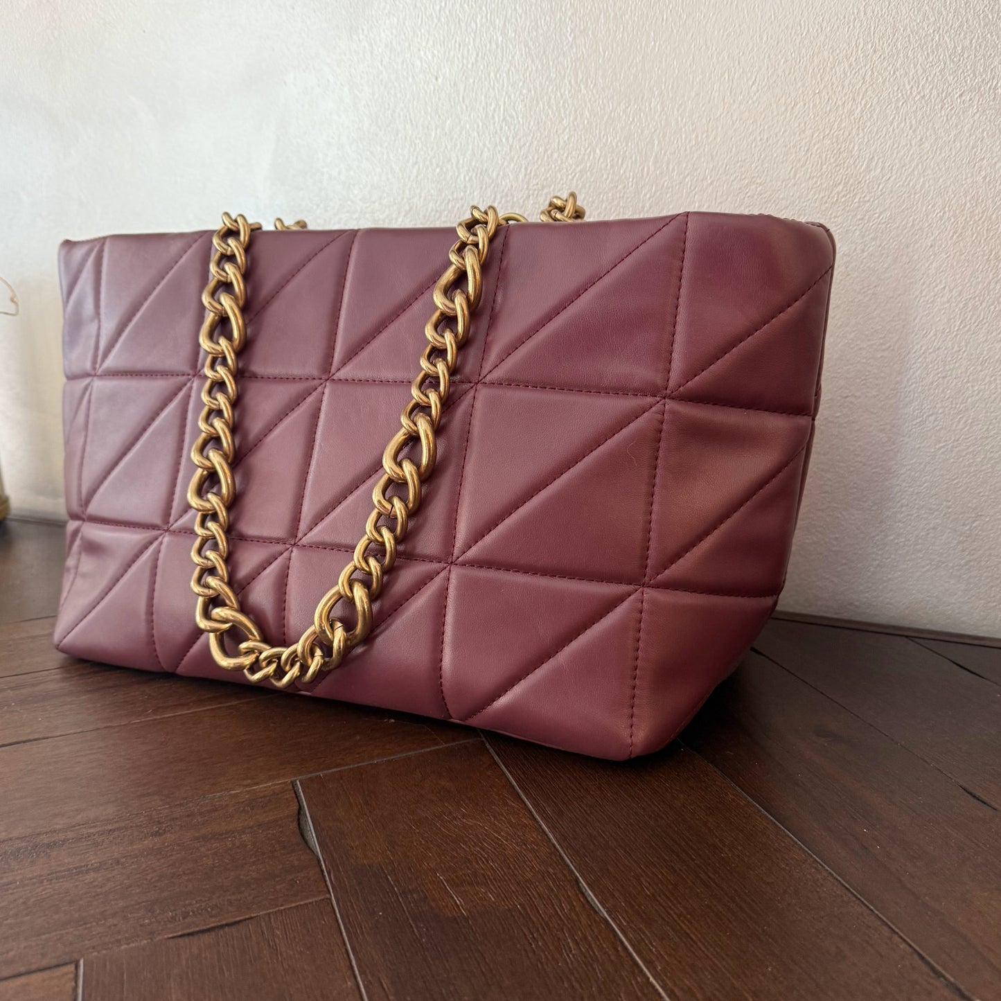 Bolso acolchado con asas de cadena dorada.