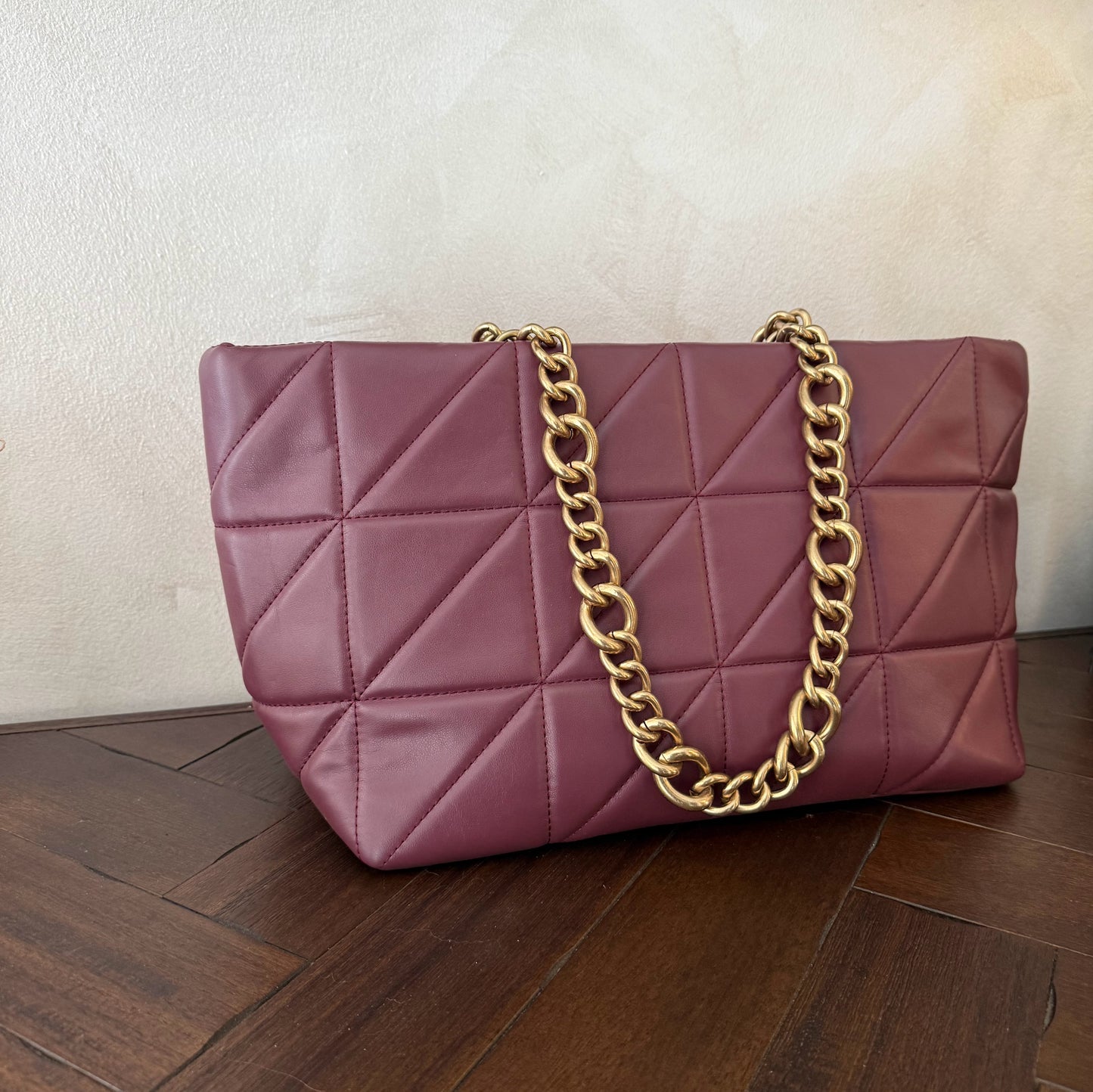 Bolso acolchado con asas de cadena dorada.