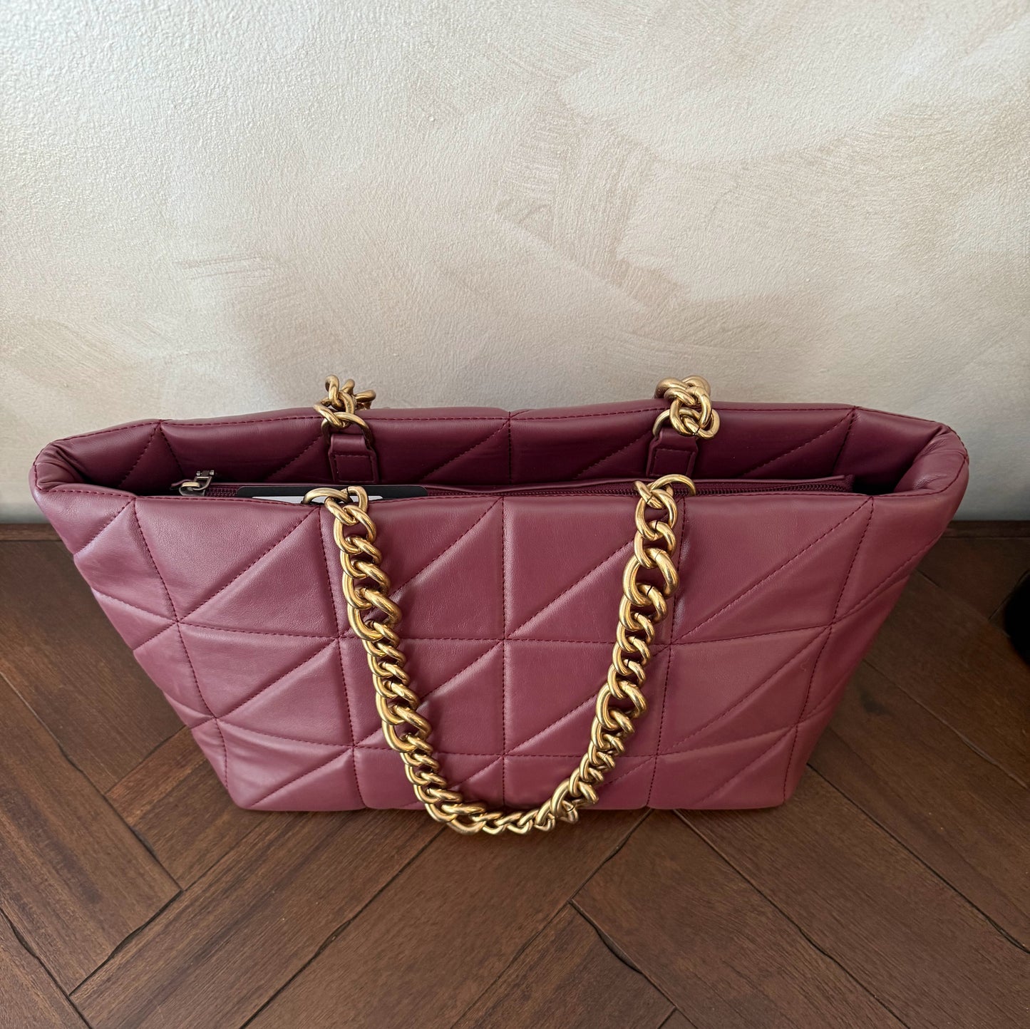 Bolso acolchado con asas de cadena dorada.