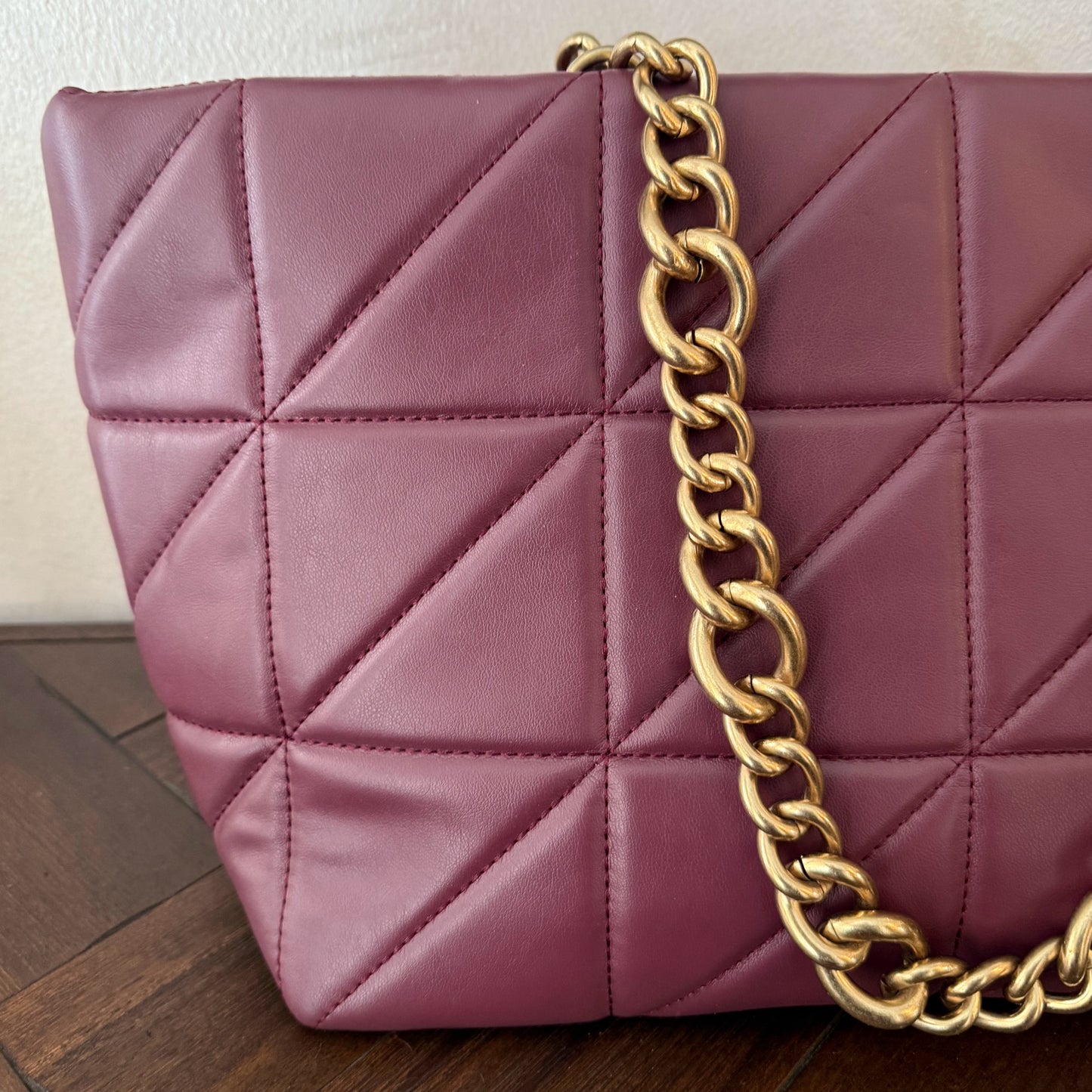 Bolso acolchado con asas de cadena dorada.