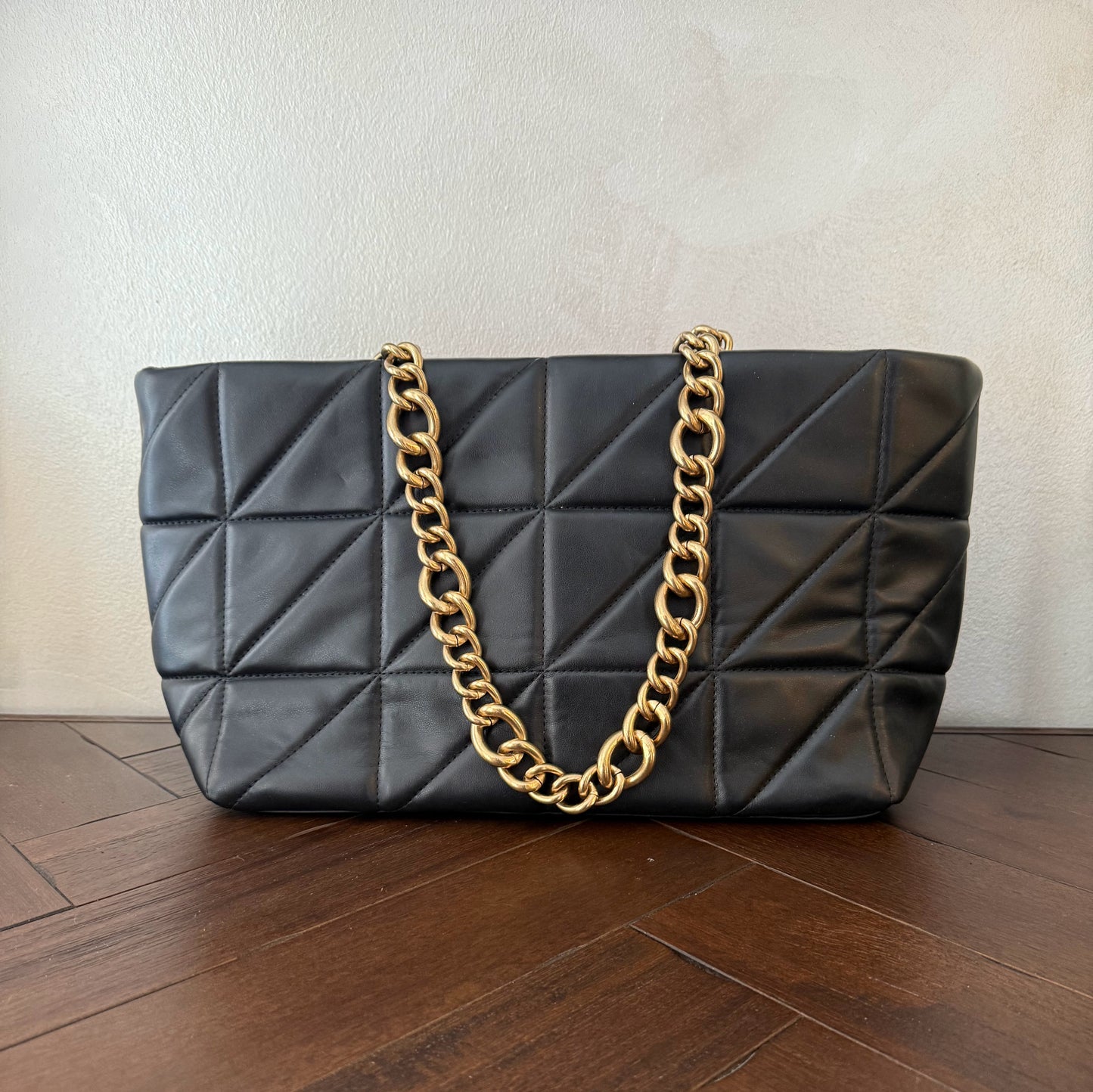 Bolso acolchado con asas de cadena dorada.