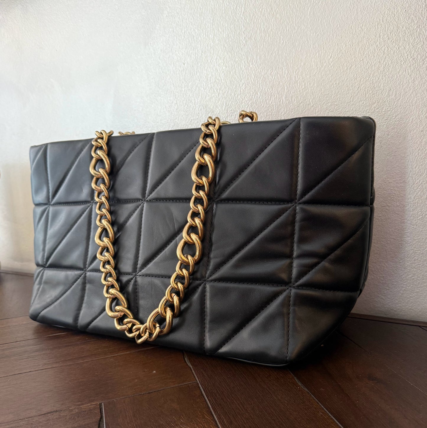 Bolso acolchado con asas de cadena dorada.