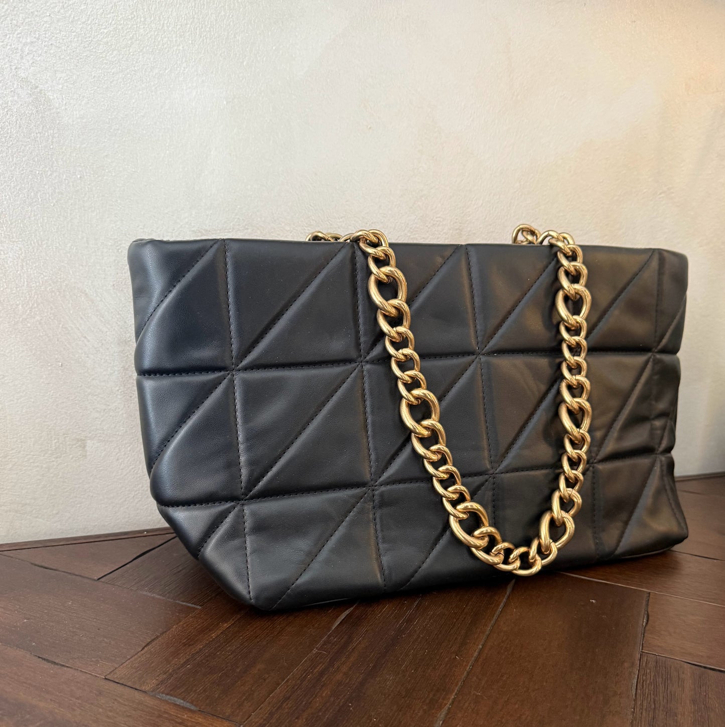 Bolso acolchado con asas de cadena dorada.