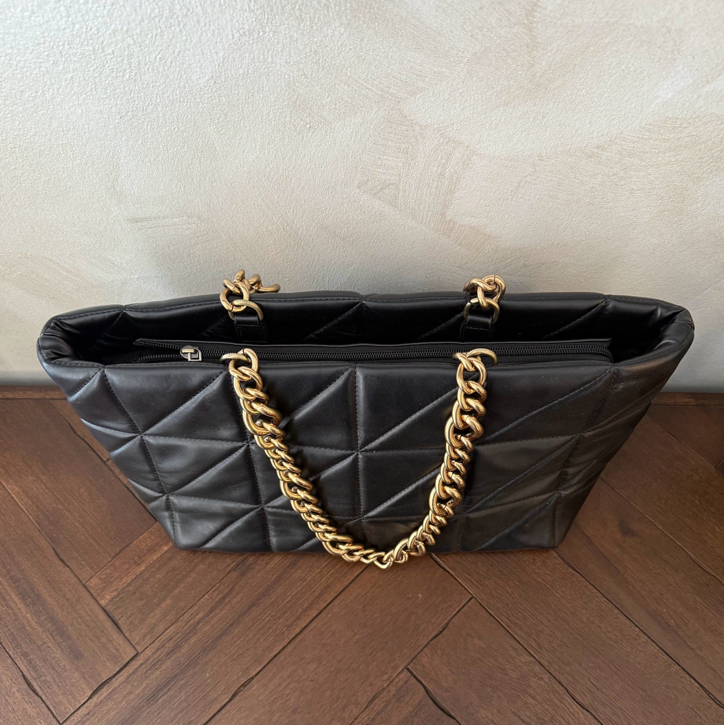 Bolso acolchado con asas de cadena dorada.